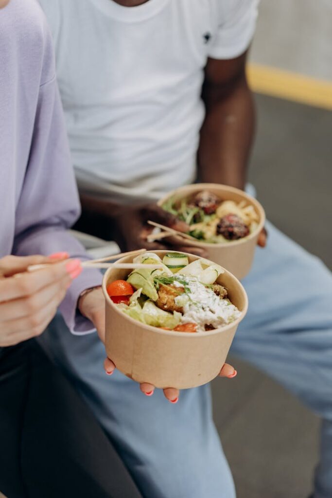 Two people enjoying nutritious salad bowls with fresh ingredients indoors.