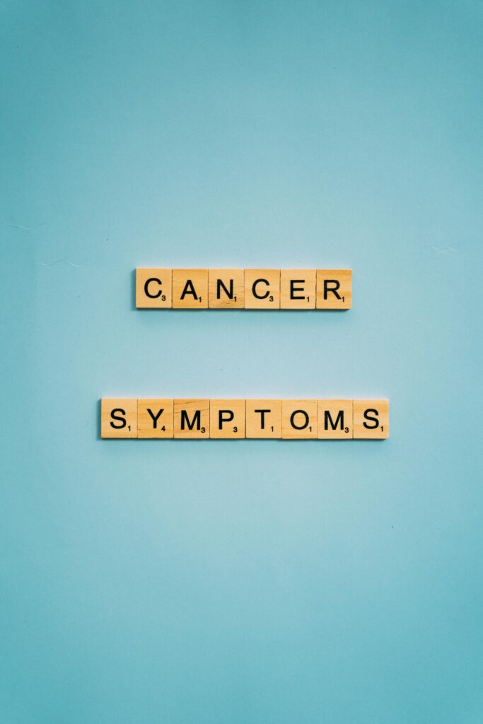 Scrabble tiles spelling 'cancer symptoms' on a blue background, emphasizing awareness.